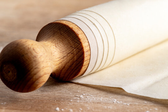 Positioned diagonally on a wooden cutting board, the rolling pin is elegantly wrapped in delicate layers of phyllo dough, ready to be transformed into a culinary masterpiece.