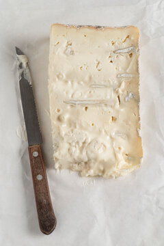 A slice of italian cheese named 'Gorgonzola' resting on the paper that wrapped it.