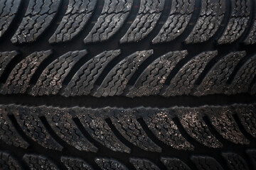 Worn tread surface: The tire's tread displays visible signs of use, with dirt and small particles on its surface.