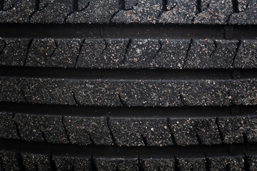 Close-up of tire tread: The image showcases the detailed texture of a car tire's tread, with embedded dirt and dust.
