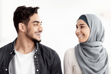 Happy muslim family cleaning their new apartment, holding house-keeping supplies and looking at...