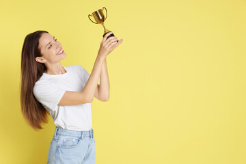 Happy winner with gold trophy cup on yellow background, space for text