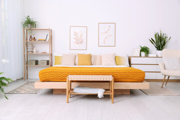 Large bed near white wall in room. Stylish bedroom interior