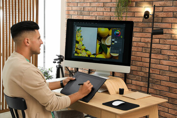 Professional retoucher working on graphic tablet at desk in office