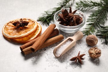 Different spices, dried orange slices and fir tree branches on light grey table, closeup. Christmas season