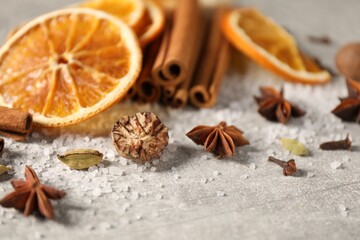 Different spices and dried orange slices on light grey table, closeup. Christmas season
