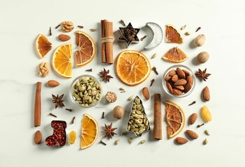 Different spices and dried orange slices on white marble table, flat lay. Christmas season