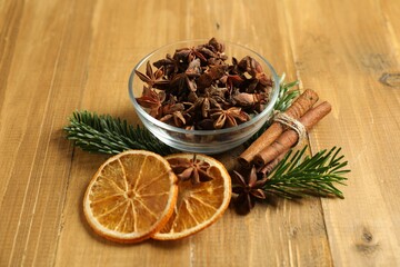 Different spices, dried orange slices and fir tree branches on wooden table. Christmas season