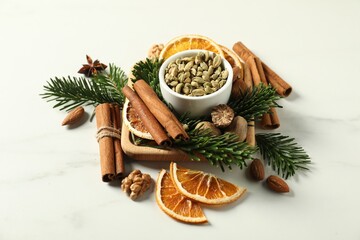 Different spices, dried orange slices and fir tree branches on white marble table. Christmas season