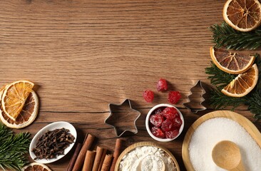 Different aromatic spices and fir tree branches on wooden table, flat lay with space for text. Christmas season