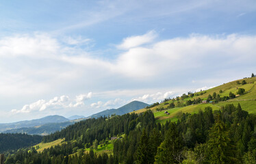 Picturesque view of lush green hills and dense forest under a clear blue sky. The serene rural...