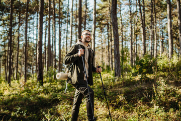 Young caucasian man hiking or trekking through the forest	