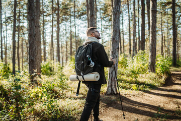 Young caucasian man hiking or trekking through the forest	