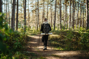 Young caucasian man hiking or trekking through the forest	