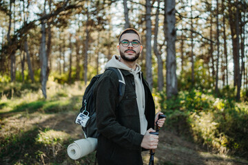 Young caucasian man hiking or trekking through the forest	