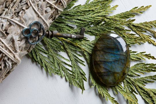 A top view image of a labradorite crystal on a cedar bow with a white sage smudge stick.
