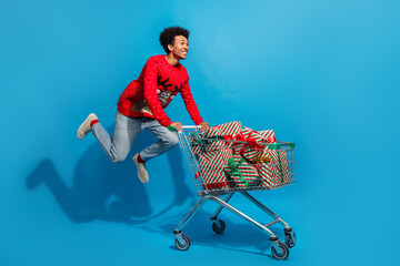 Full size photo of pretty young male jump push shopping cart gifts wear red christmas sweater...