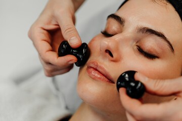 Woman receiving facial treatment with massage tools for relaxation and beauty