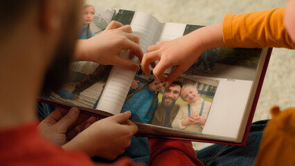 Back view Caucasian father little girls daughters school kids watching family album put photo collection memories parent man dad children watch pictures evening home weekend give high five teamwork