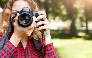 Young female student taking photos in the park with camera. Photography classes, education and remote working concept, copy space, closeup