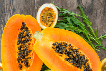 Papaya fruit passion fruit and rucola on a dark wooden background