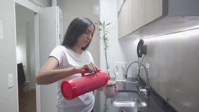 young latin woman puts water from a thermos to her mate to start drinking mate