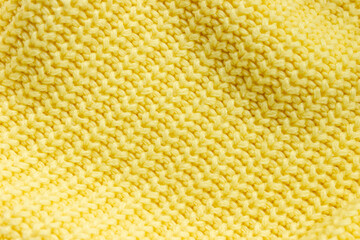 Texture of knitted lemon yellow pullover close-up placed diagonally. Selective soft focus, space for text