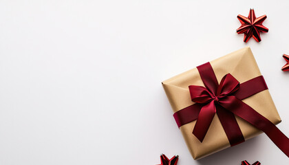 Obraz premium A beautifully wrapped gift box with a red ribbon and stars, set against a clean white background, perfect for celebrations and special occasions.