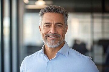 Fototapeta premium Smiling middle aged businessman portrait in office setting warm light professional confident manager executive