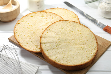 Delicious cut sponge cake and knife on white wooden table