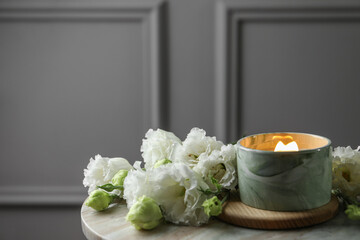 Burning candle and beautiful flowers on marble table. Space for text