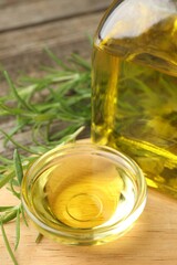 Cooking oil and rosemary on wooden table, closeup