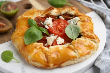 Tasty galette with tomato, basil and cheese on white table, closeup