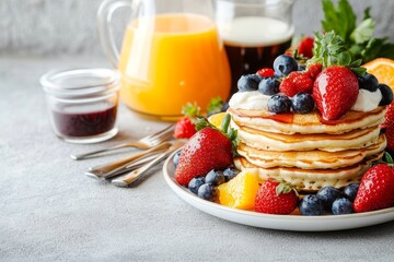 Breakfast spread with pancakes strawberries blueberries yogurt orange juice on gray table healthy food