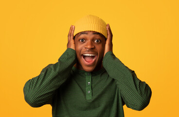 Amazing Offer. Portrait Of Surprised Black Hipster Guy Touching Head With Excitement, Amazed Happy Young African American Man Exclaiming OMG While Standing Over Yellow Background, Copy Space