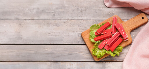 Board with tasty crab sticks on light wooden background © Pixel-Shot
