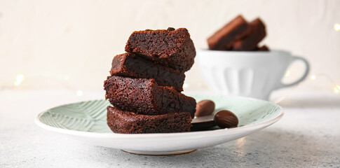 Plate with pieces of delicious chocolate brownie on light background