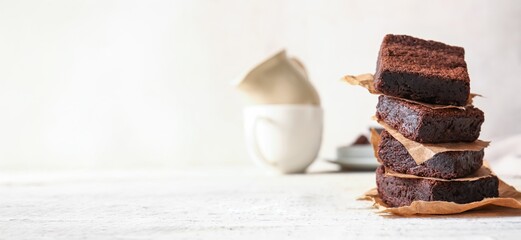 Pieces of delicious chocolate brownie on light background with space for text