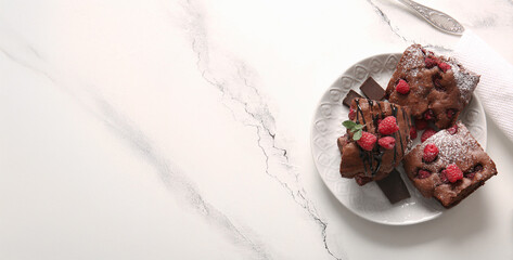 Plate with pieces of raspberry chocolate brownie on white background