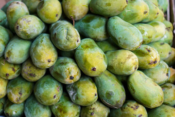 Close-up view of a pile of fresh green mangoes, ready for sale. A Bountiful Harvest of Green Mangoes Background.