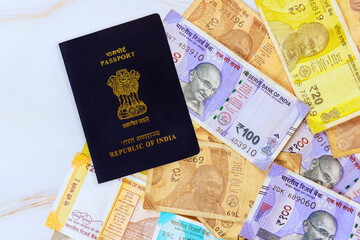 Indian passport rests on collection of colorful Indian rupees money banknotes, showcasing travel currency.