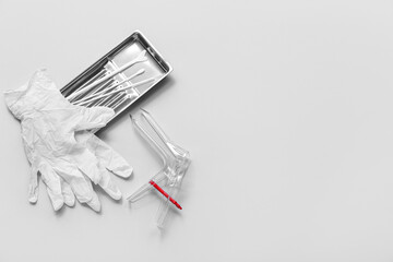 Medical gloves with gynecological speculum and pap smear test tools on light background