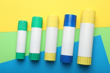 Sticks of glue on color background, flat lay