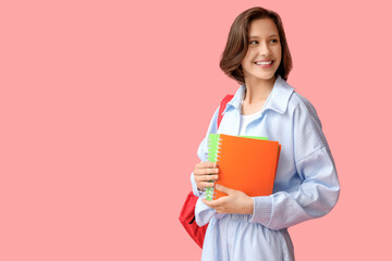 Beautiful female student with backpack and notebooks on pink background