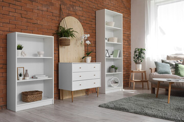 Chest of drawers with orchid and shelving units in interior of living room