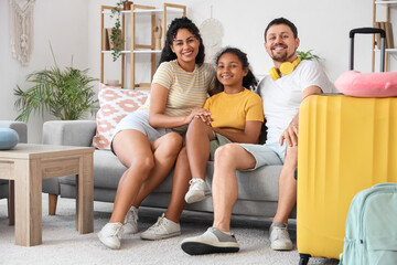 Happy family with packed suitcase for travel sitting on sofa at home