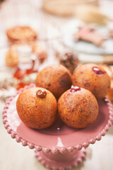 Traditional Colombian buñuelos served in a metal baking tray, resting on a wooden board. These golden, crispy cheese fritters are beautifully decorated with dulce de leche and fruit jam fillings