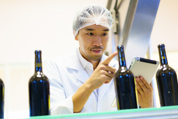 QA officer performs quality inspection of beverage bottles.