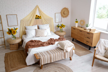 Interior of light bedroom with cozy bed and beautiful sunflowers