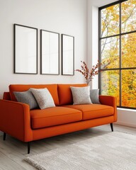 A stylish orange sofa with decorative cushions, positioned by a large window showcasing autumn foliage and three empty frames on the wall.